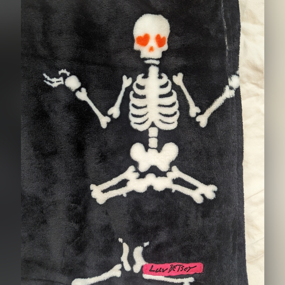 Black plush throw blanket with red heart eyed skeletons all over